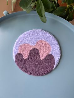 a purple and pink rug sitting on top of a blue table next to a potted plant