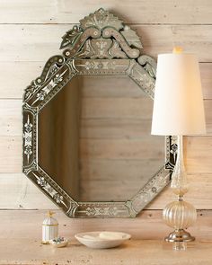 a mirror sitting on top of a wooden table next to a lamp and a vase