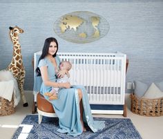 a woman sitting in a chair holding a baby next to a giraffe statue