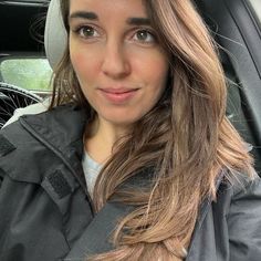 a woman sitting in the back seat of a car looking at the camera and smiling