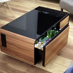 a wooden table with an open drawer containing beer bottles and cans in it on a hard wood floor