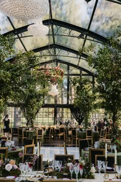 an indoor dining area with tables and chairs set up for a formal function under a glass roof