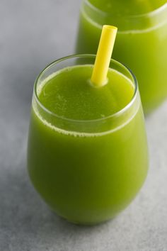 two glasses filled with green smoothie on top of a table