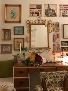 a desk with a mirror, chair and many pictures on the wall in front of it