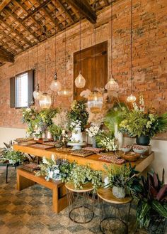 a long table with plants on it in front of a brick wall and wooden ceiling