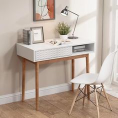 a white desk with a chair next to it and a framed painting on the wall