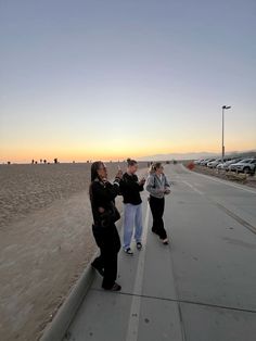 three people are standing on the sidewalk talking to each other