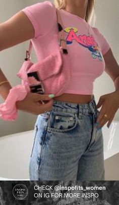 a woman in a pink shirt is holding a cell phone and looking at her stomach