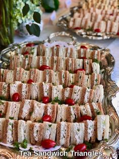 several trays of sandwiches with cherry tomatoes on them sitting on a silver platter