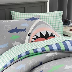 a child's bed with shark and checkered pillowcases on the headboard