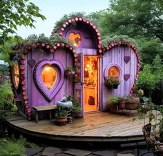 a purple heart shaped house in the middle of a garden with potted plants on it