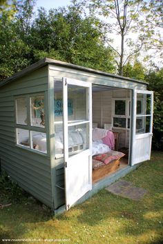 a small shed with a bed in it and some windows on the side of it