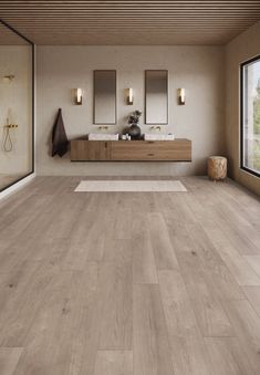 a large bathroom with wooden floors and mirrors on the wall, along with two sinks