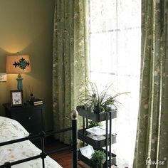 a bed room with a neatly made bed and a planter on the end table