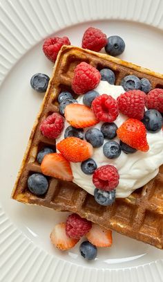 waffles topped with berries and whipped cream on a white plate