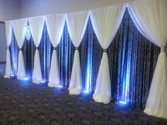 a room with white curtains and lights on the wall, along with dark carpeting