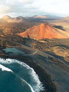 an aerial view of the ocean and land near some mountains with water in front of it