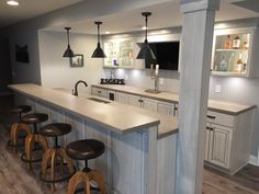 a kitchen with an island and bar stools in the center, along with several lights