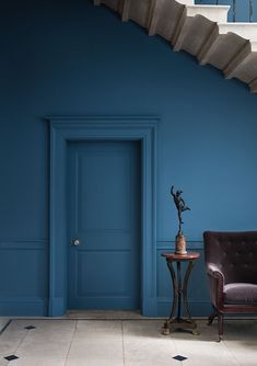 a room with blue walls and a chair next to a table on a tiled floor