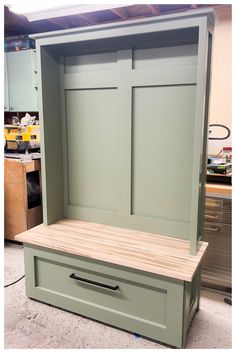 a wooden bench with two doors and drawers on the bottom shelf, in a shop