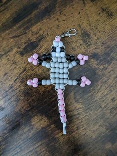 a cross made out of beads sitting on top of a wooden table