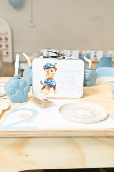 a lunch box sitting on top of a table next to plates and utensils