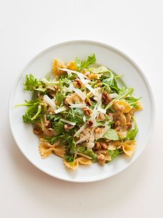 a white plate topped with pasta and greens