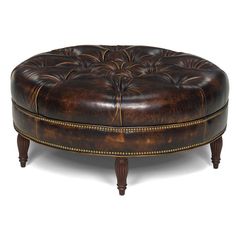 a brown leather ottoman sitting on top of a wooden table