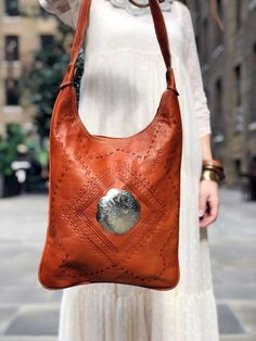 Beautiful large hippie leather bag in burnt orange. It's a lovely large tribal leather tote in bohemian look. This is a handmade women's Moroccan leather bag with ethnic tooled leather pattern and leather stitches. In addition, the bag has been embellished with an filigree engraved flower stud as centrepiece. The bag has an amazing rich tan colour, like burnt orange which makes the silver stud pop even more. It's a beautiful piece of leather craft, lightweight yet sturdy. The bag has a practical Tooled Leather Pattern, Leather Stitches, Vintage Tooled Leather Purse, Leather Tooling Patterns, Tooled Leather Bag, Tooled Leather Purse, Brown Crossbody Bag, Moroccan Leather, Floral Purse