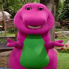 an inflatable pink dinosaur with a green t - shirt standing next to a tree