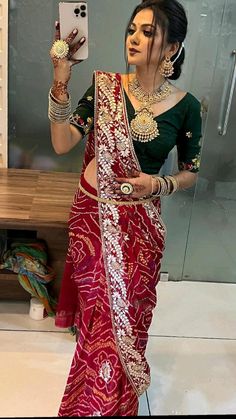 a woman in a red and gold sari taking a selfie