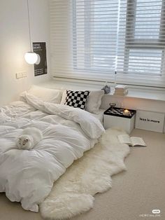 a white bed sitting in a bedroom next to a window covered in blankets and pillows