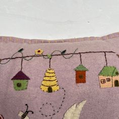 a purple pillow with birds and houses on the front, hanging from a line above it