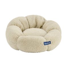 a white dog bed with a blue tag on the front and bottom, it is made out of sheep fur