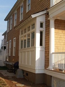 an outside view of a house with white railings and wood siding on the side