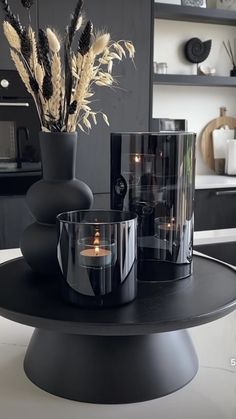 there are candles and vases on the table in this kitchen setting with black cabinets