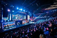 a large group of people playing video games on the big screen in a convention hall