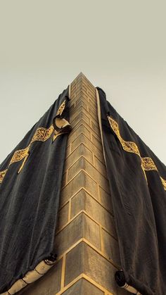 the top of a tall building with a black and gold cloth covering it's sides