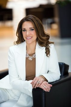 a woman sitting in a chair wearing a white suit