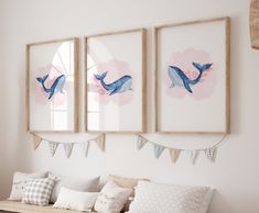 three framed whale pictures hang on the wall above a bench with pillows and throw pillows