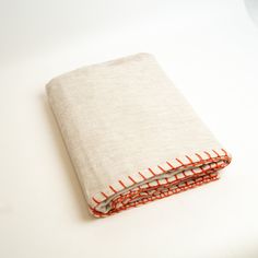 a white cloth with red stitchs on it sitting next to a folded book cover