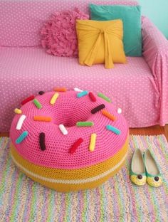 a pink knitted donut pillow sitting on top of a bed