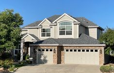 a large house with two car garages in front of it and trees around the driveway