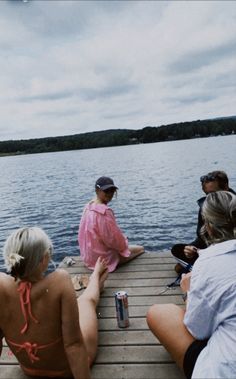 four people sitting on a dock near the water