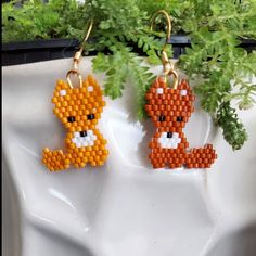 two small pixelated animals are hanging from earrings