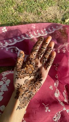 a woman's hand with hennap on top of it and grass in the background