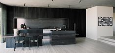 a modern kitchen with black counter tops and wooden flooring, along with stairs leading up to the upper level