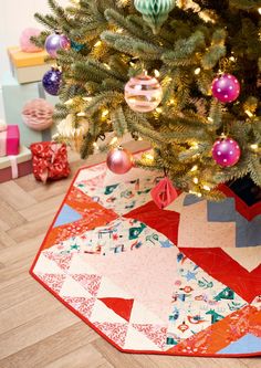 a christmas tree with ornaments on it and a colorful quilted table runner under the tree