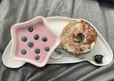 a white plate topped with a donut next to a bowl of blueberries