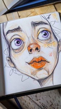 a drawing of a woman's face with blue eyes and orange lips on a notebook